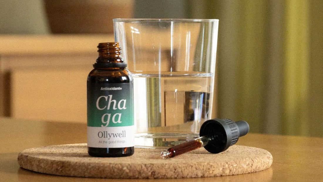 Liquid extract of the Chaga functional mushroom, standing on a table along with a glass of water.